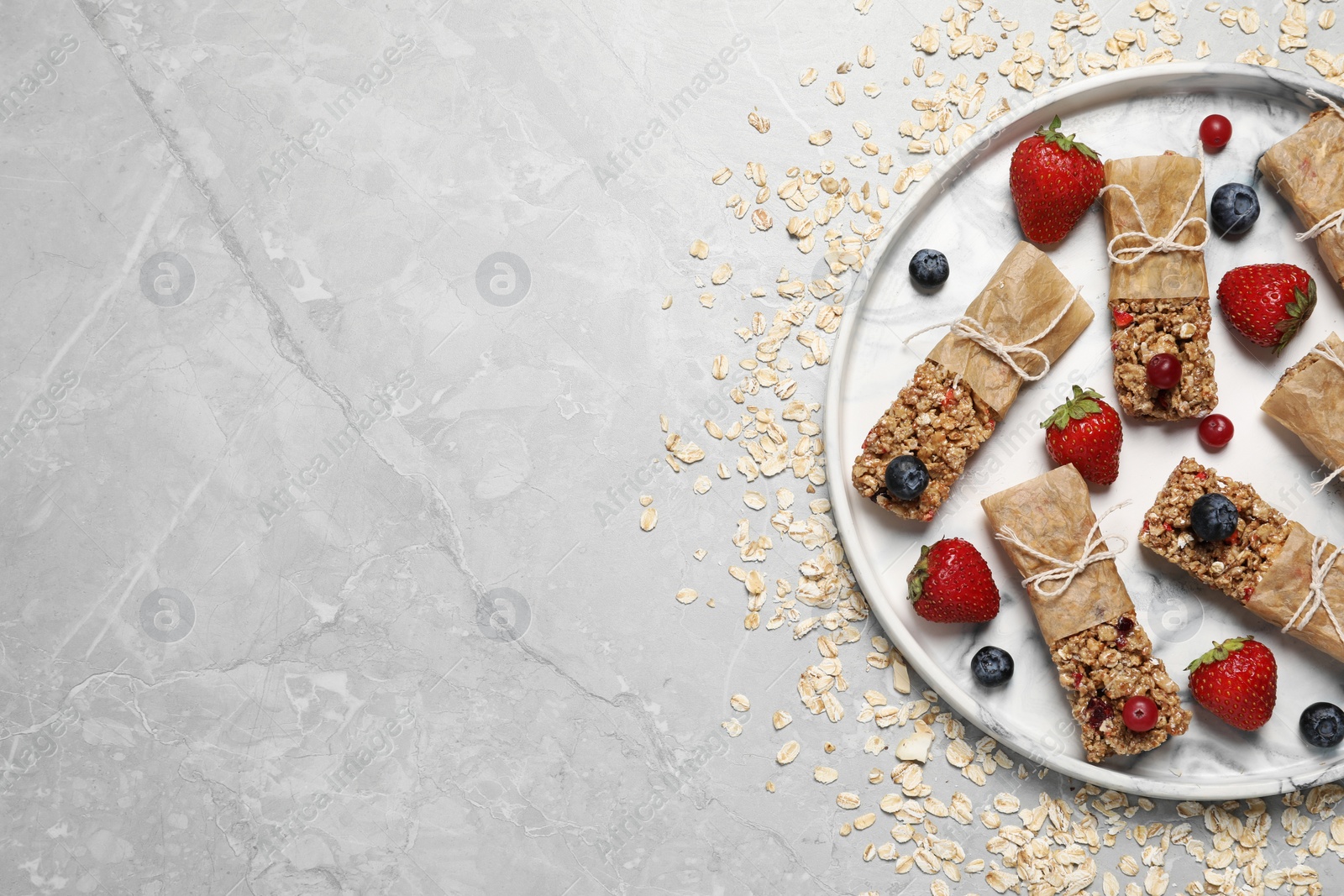 Photo of Tasty granola bars and ingredients on light grey table, top view. Space for text