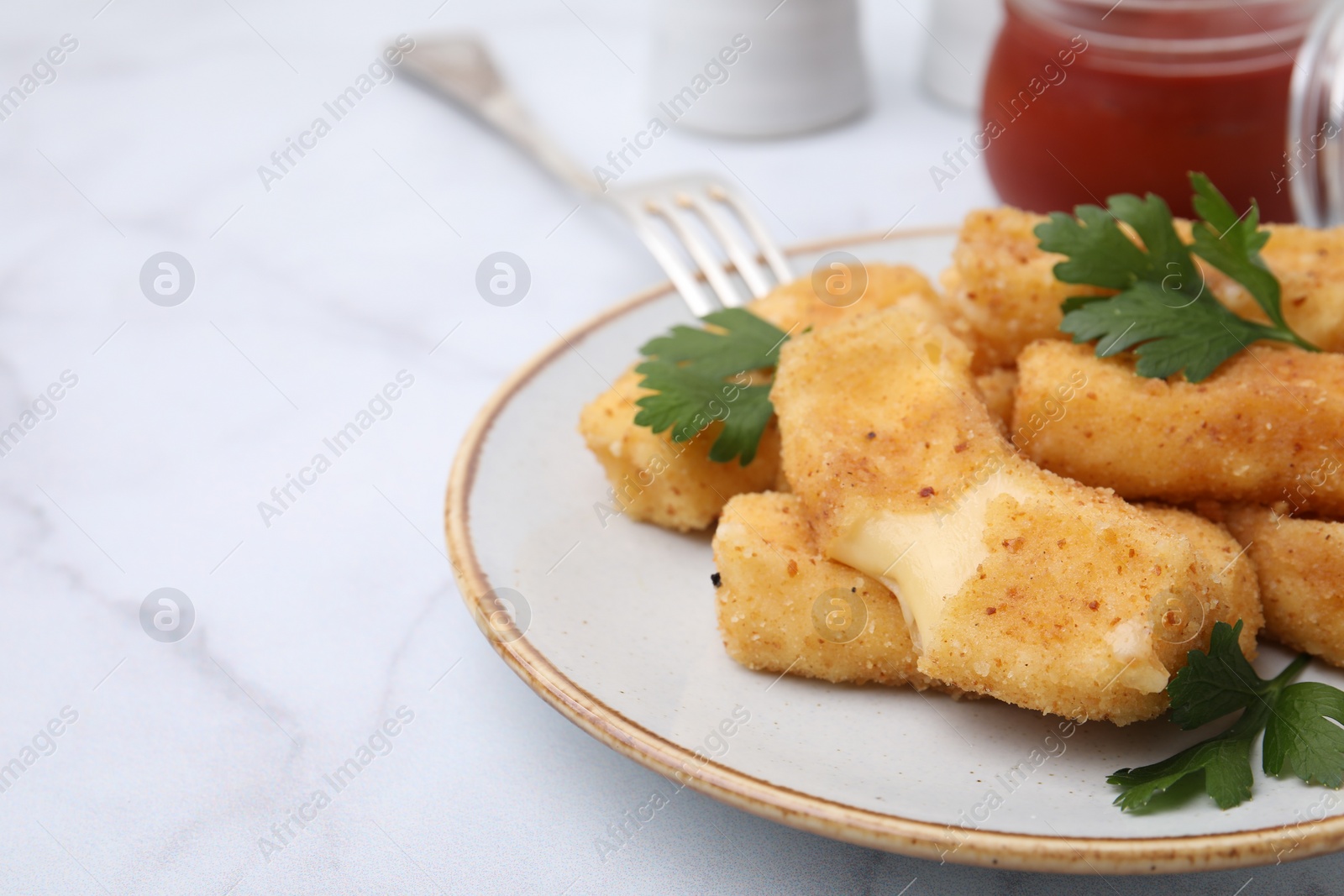 Photo of Plate with tasty fried mozzarella sticks and parsley on white marble table, closeup. Space for text