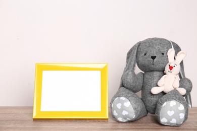 Photo frame and adorable toy bunnies on table against light background, space for text. Child room elements