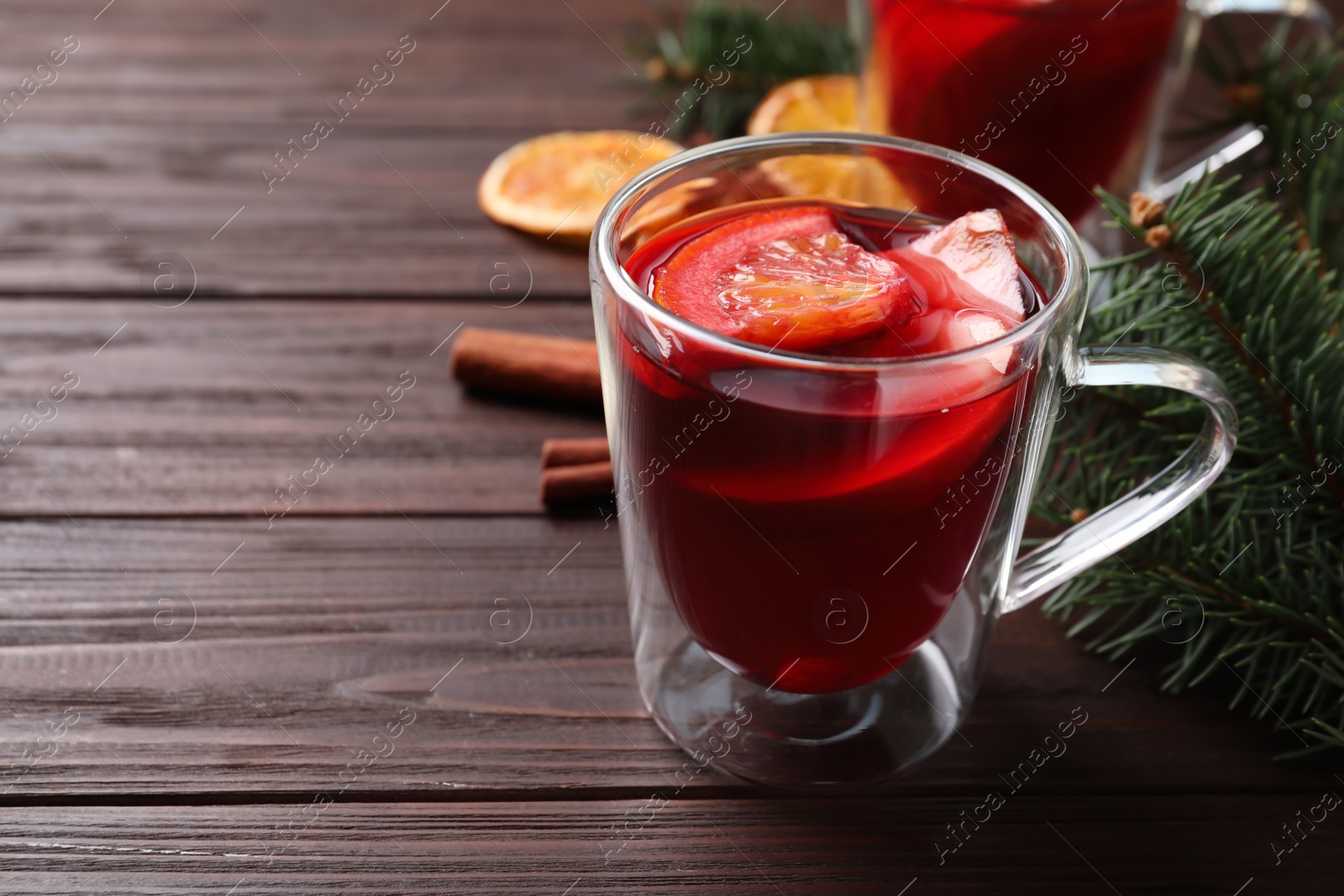 Photo of Delicious hot mulled wine on wooden table, space for text