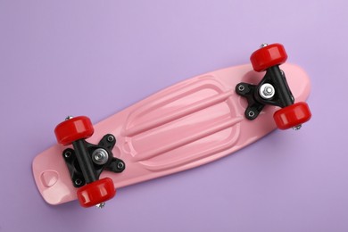 Photo of Pink skateboard on lilac background, top view