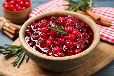 Photo of Fresh cranberry sauce with rosemary on wooden board