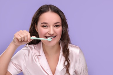 Photo of Woman with braces cleaning teeth on violet background. Space for text
