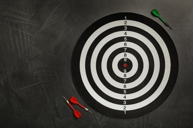 Photo of Dart board with color arrows on grey stone background, top view. Space for text