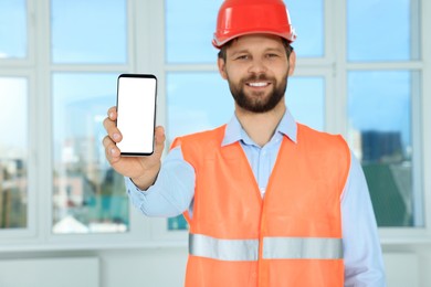 Man in reflective uniform with phone indoors