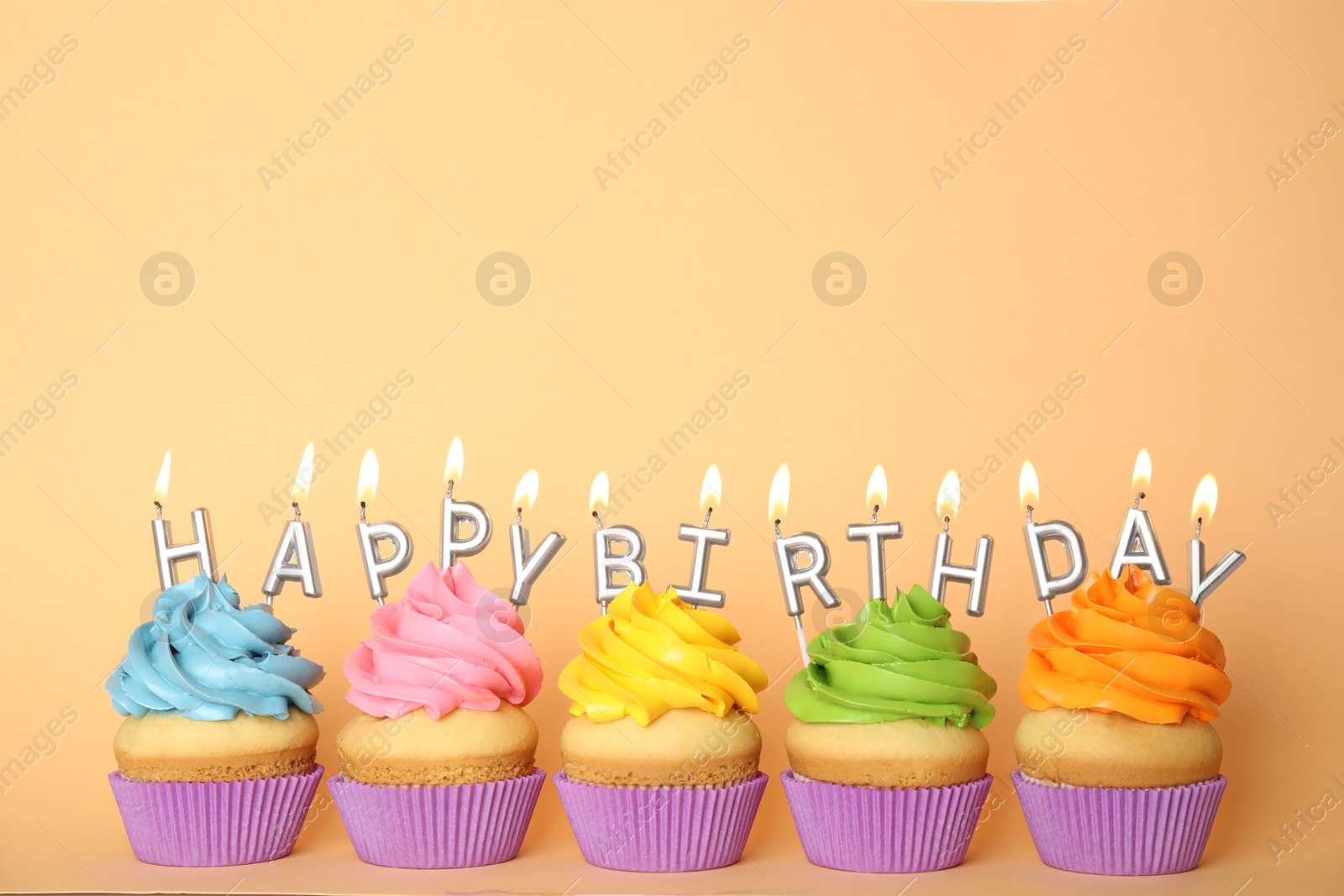 Photo of Birthday cupcakes with burning candles on beige background. Space for text