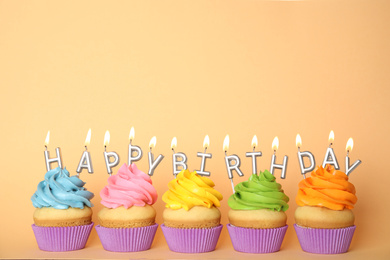 Birthday cupcakes with burning candles on beige background. Space for text