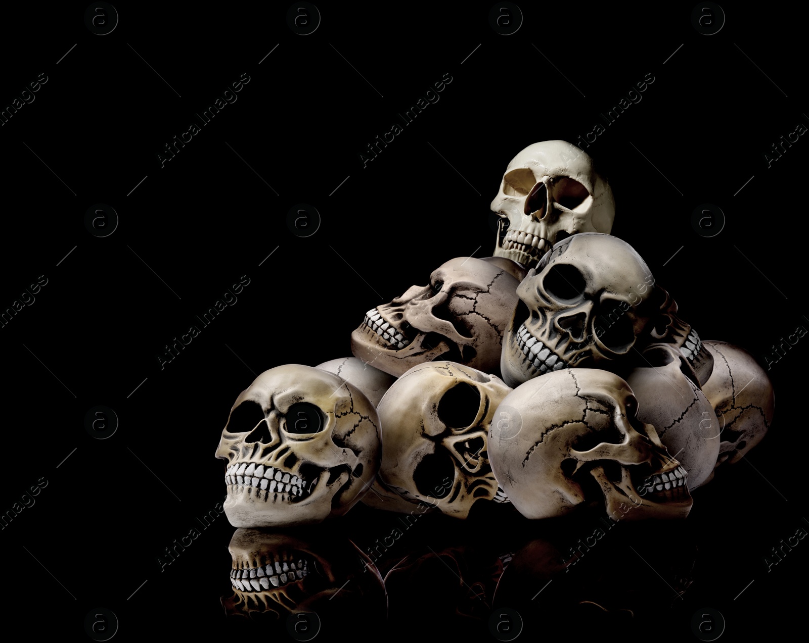 Image of Pile of scary human skulls on black background, space for text