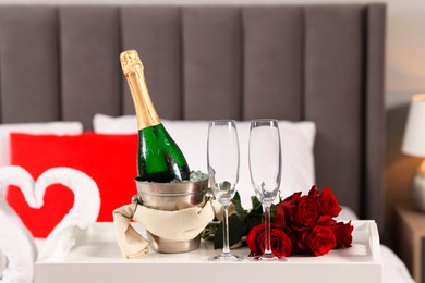 Photo of Honeymoon. Sparkling wine, glasses and bouquet of roses on table in room