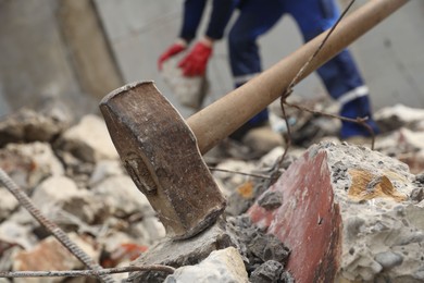 Sledgehammer on pile of broken stones. Man working outdoors, selective focus