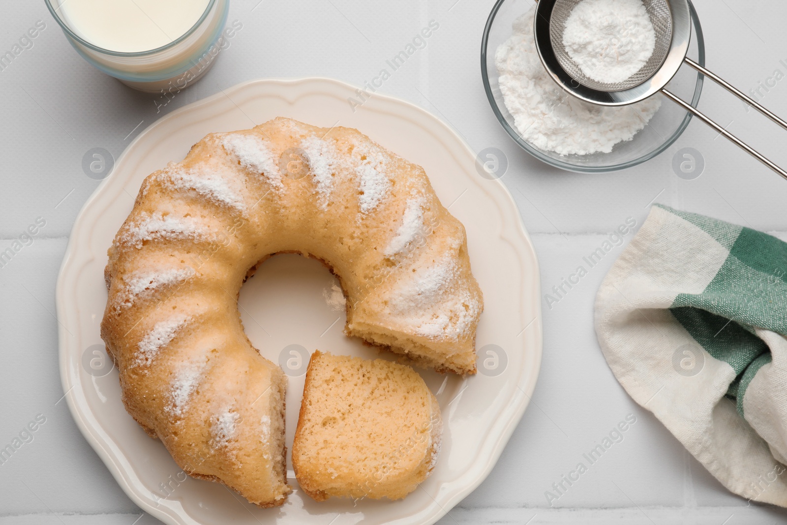 Photo of Delicious sponge cake served on white tiled table, flat lay