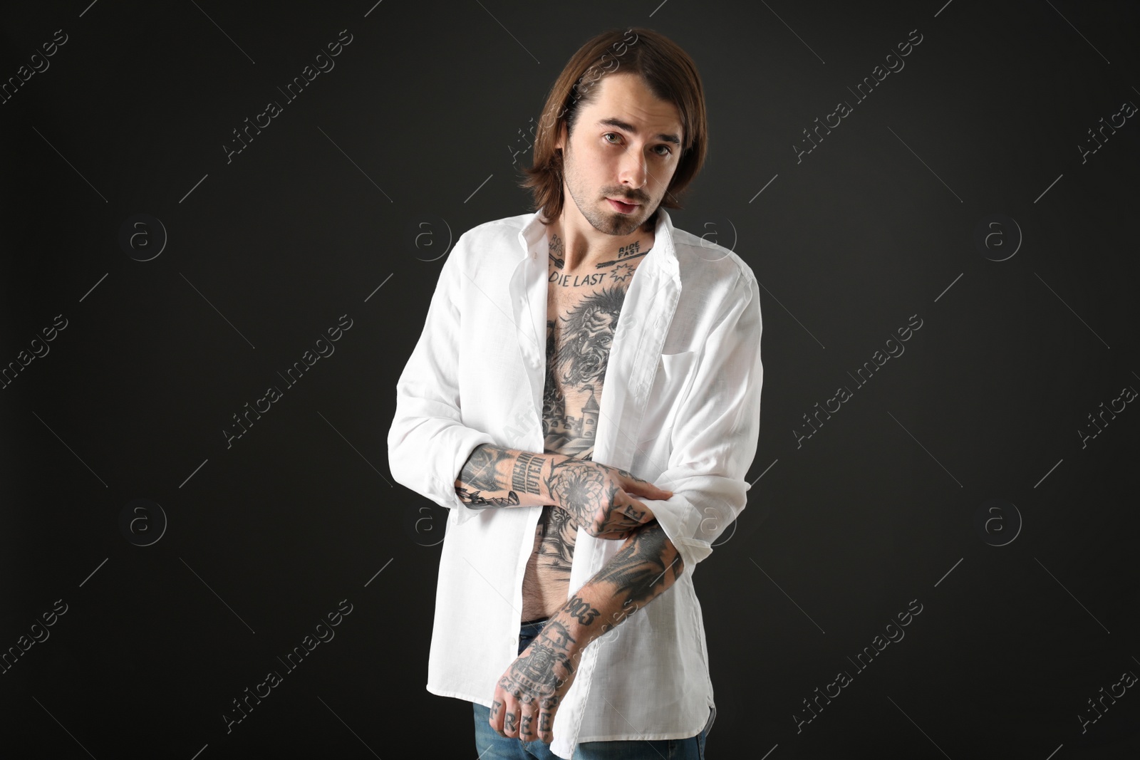 Photo of Young man with tattoos on body against black background