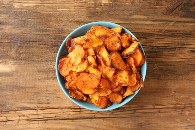 Bowl of sweet potato chips on wooden table, top view