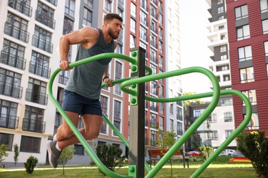Photo of Man training on parallel bars at outdoor gym, low angle view