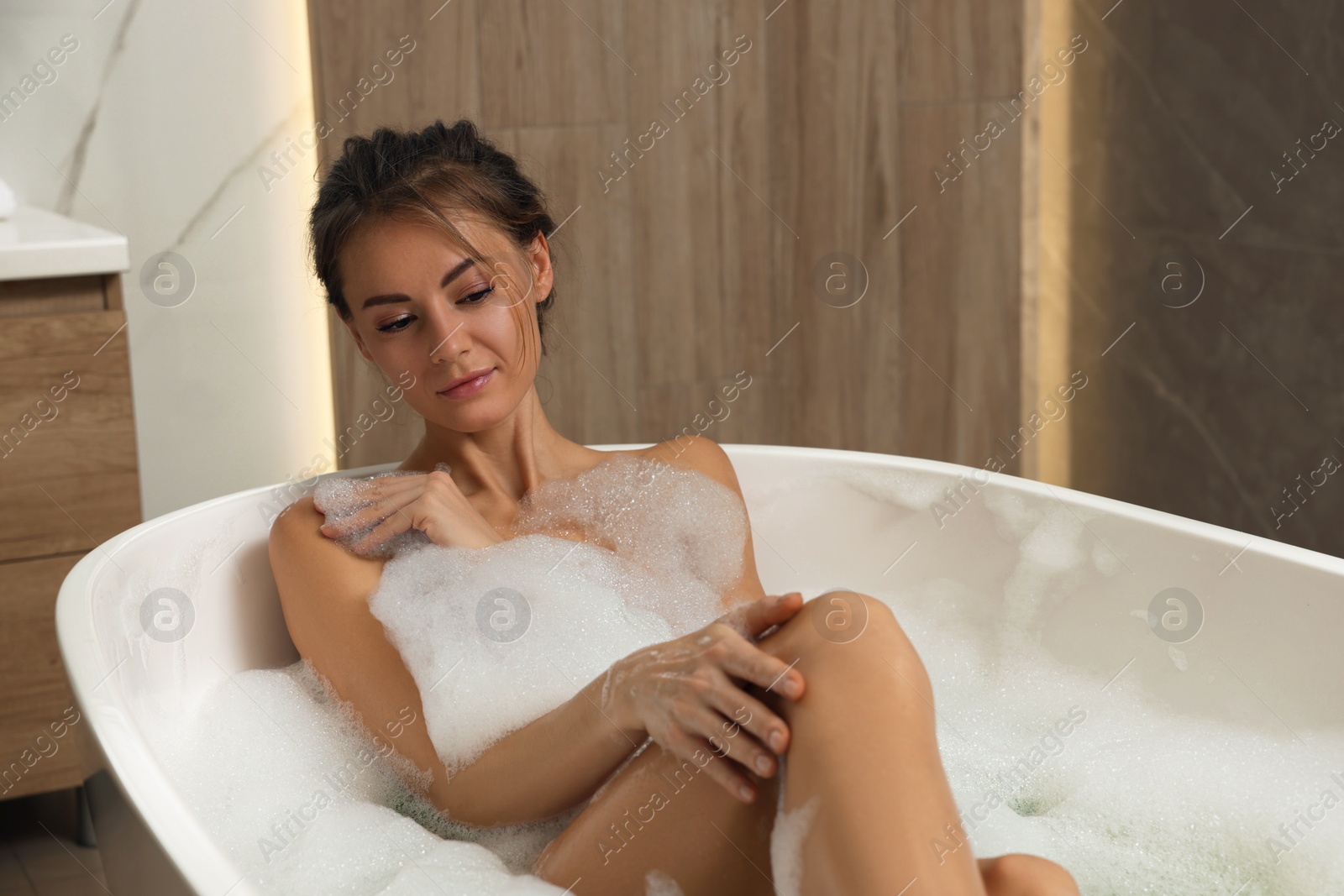 Photo of Beautiful woman taking bath with foam indoors, space for text