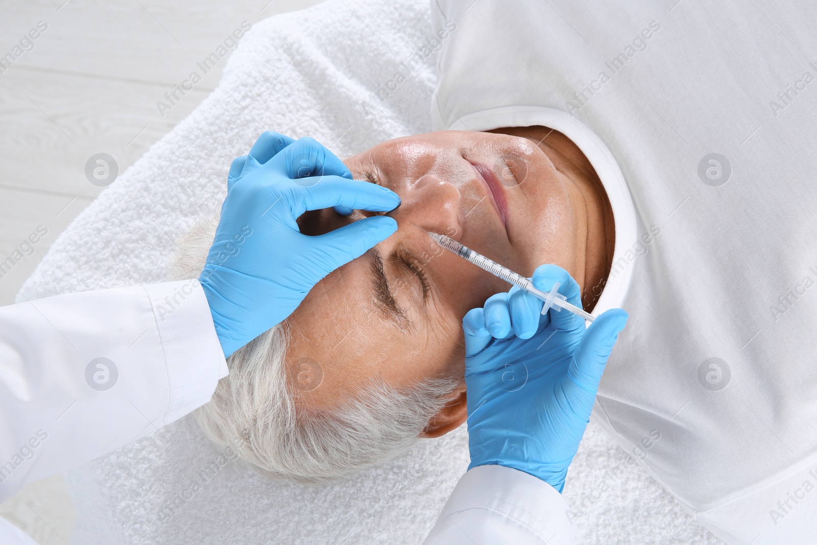 Photo of Senior man getting facial injection in clinic. Cosmetic surgery concept