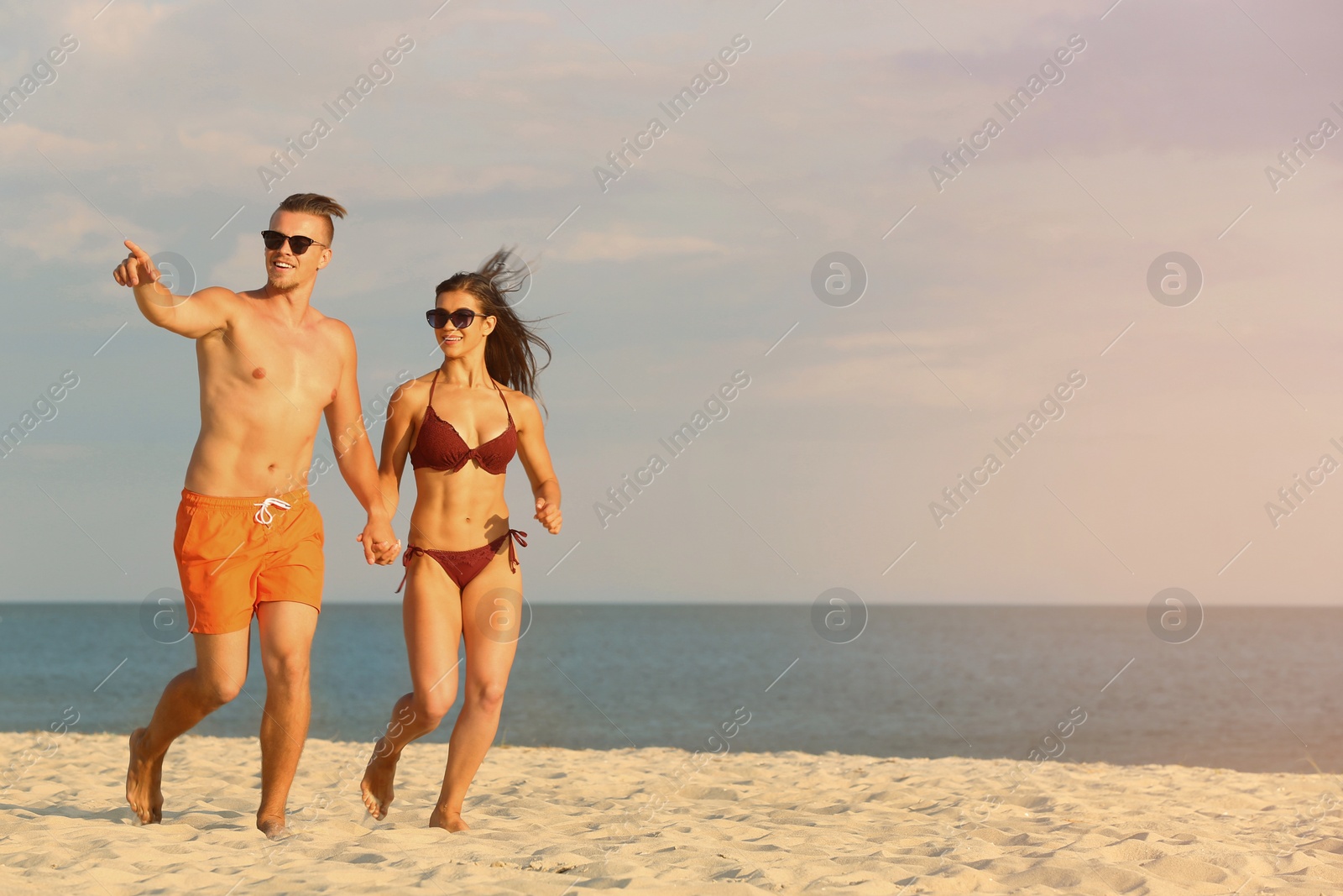 Photo of Young woman in bikini spending time with her boyfriend on beach. Lovely couple