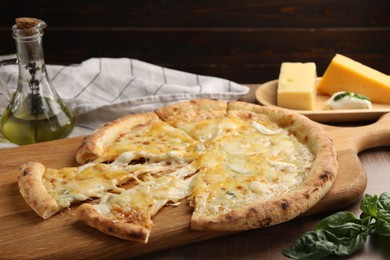 Delicious cut cheese pizza and ingredients on wooden table