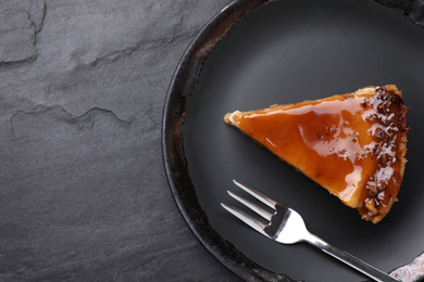 Piece of delicious cake with caramel on black table, top view