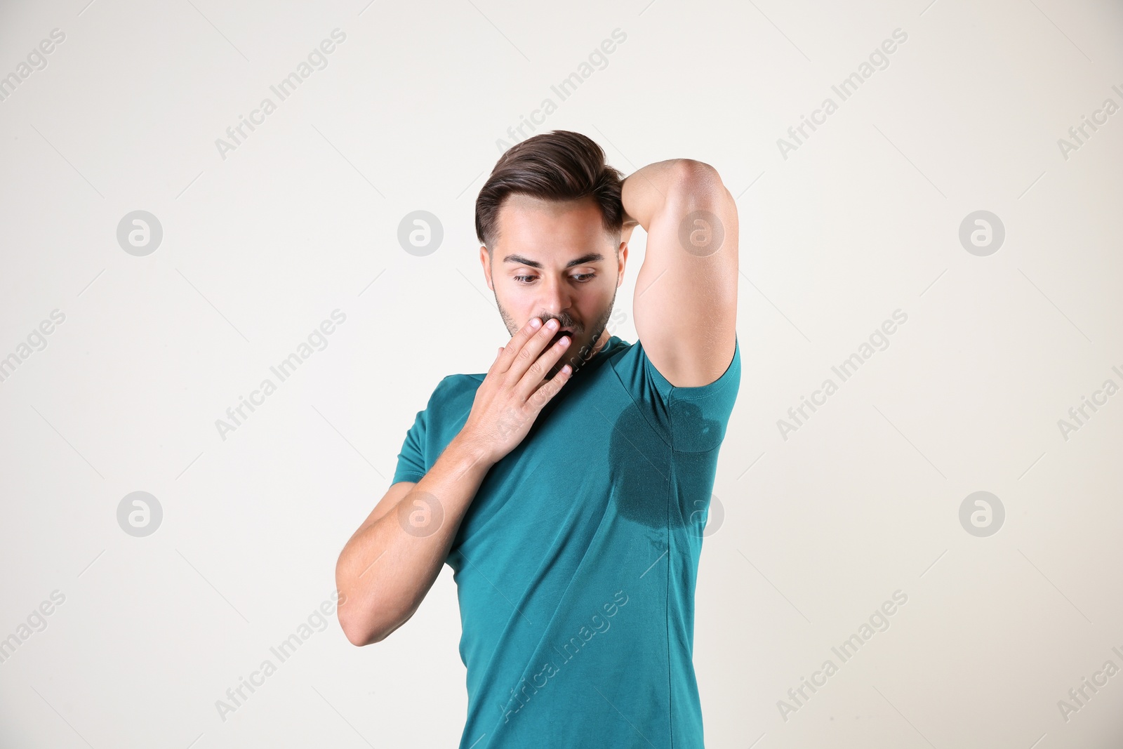 Photo of Sweaty man with stain on t-shirt against white background. Using deodorant