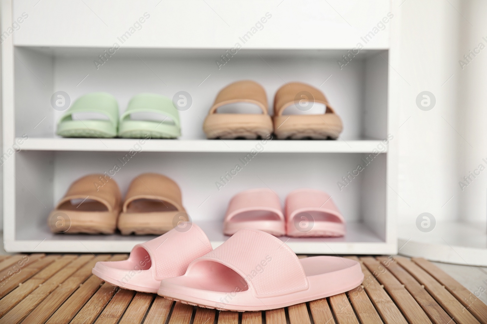 Photo of Stylish rubber slippers and storage cabinet with shoes indoors