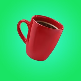 Red cup of coffee levitating on green background