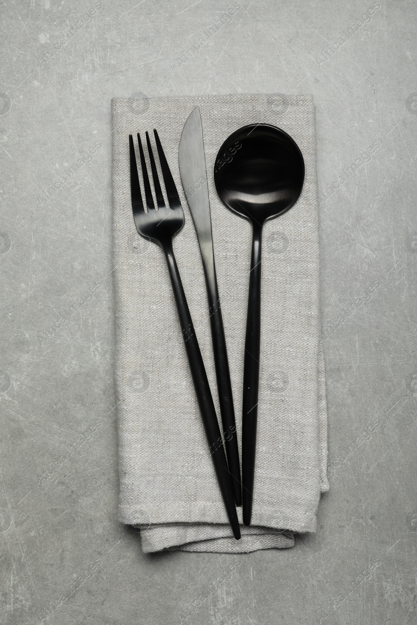 Photo of Stylish cutlery and napkin on grey table, top view