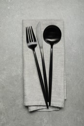 Stylish cutlery and napkin on grey table, top view