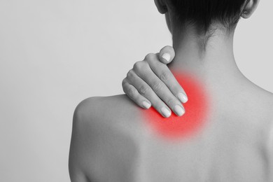 Woman suffering from neck pain on light background, closeup