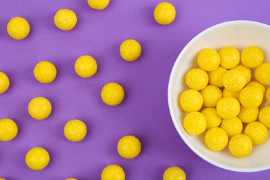 Photo of Delicious lemon chewing gums on purple background, flat lay