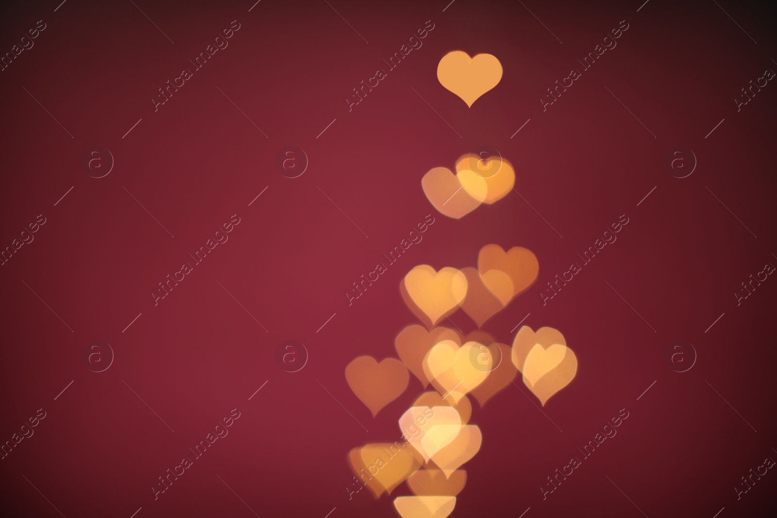 Photo of Blurred view of beautiful lights on burgundy background, space for text. Bokeh effect