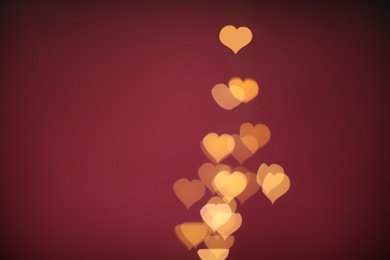 Photo of Blurred view of beautiful lights on burgundy background, space for text. Bokeh effect