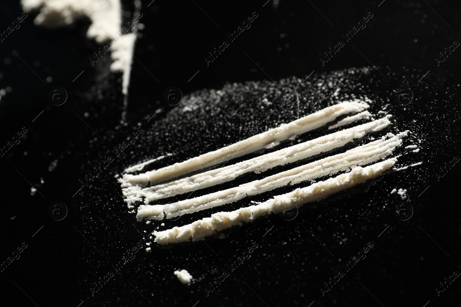 Photo of Drug addiction. Stripes of cocaine on black table, closeup