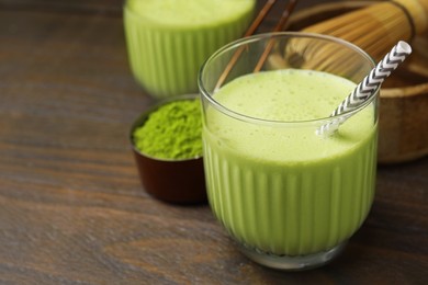 Glass of tasty matcha smoothie with straw on wooden table, closeup. Space for text