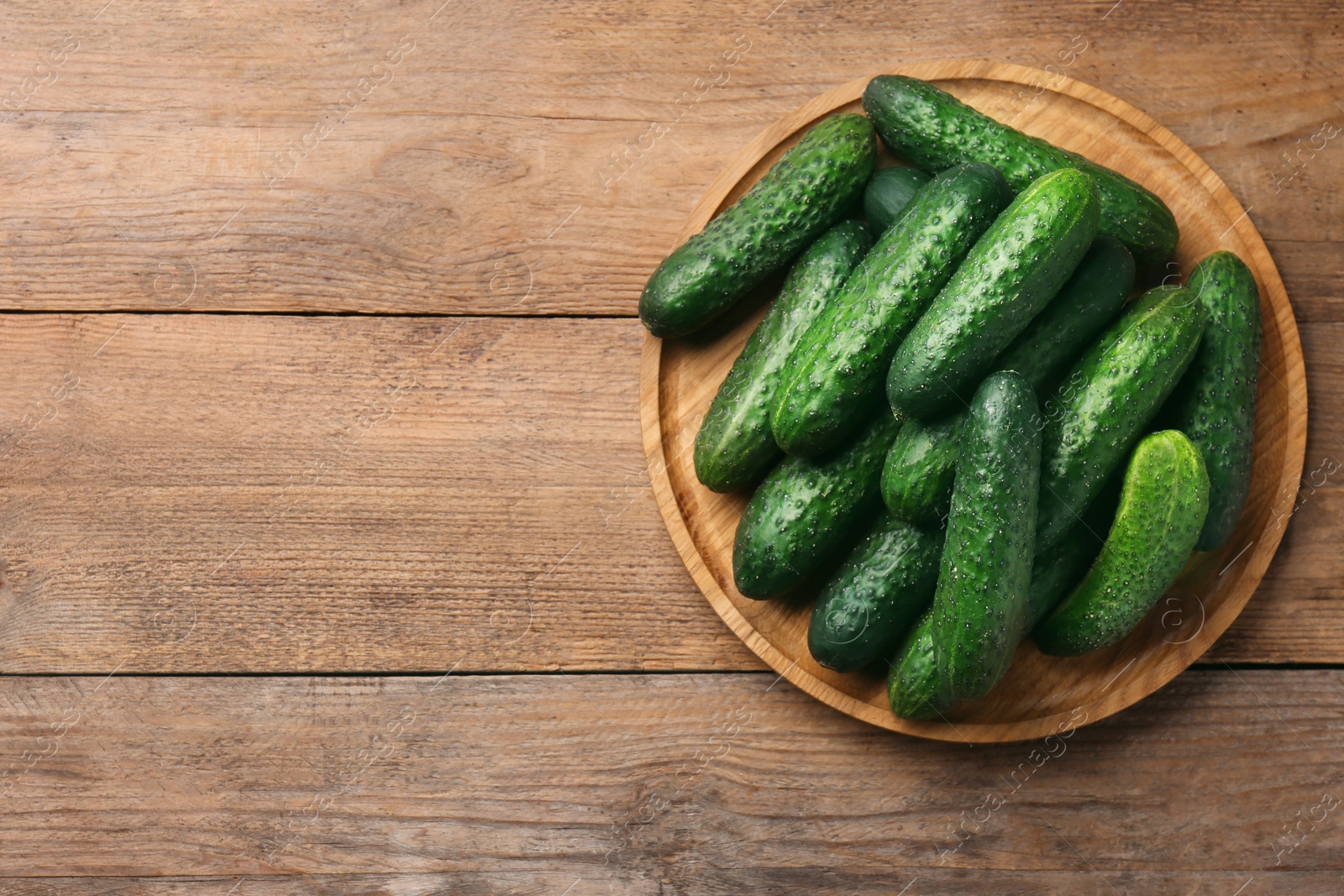 Photo of Fresh ripe cucumbers on wooden table, top view. Space for text