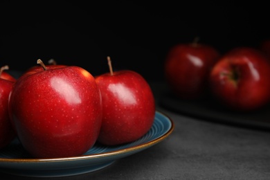 Photo of Plate with ripe juicy red apples on grey table, closeup. Space for text