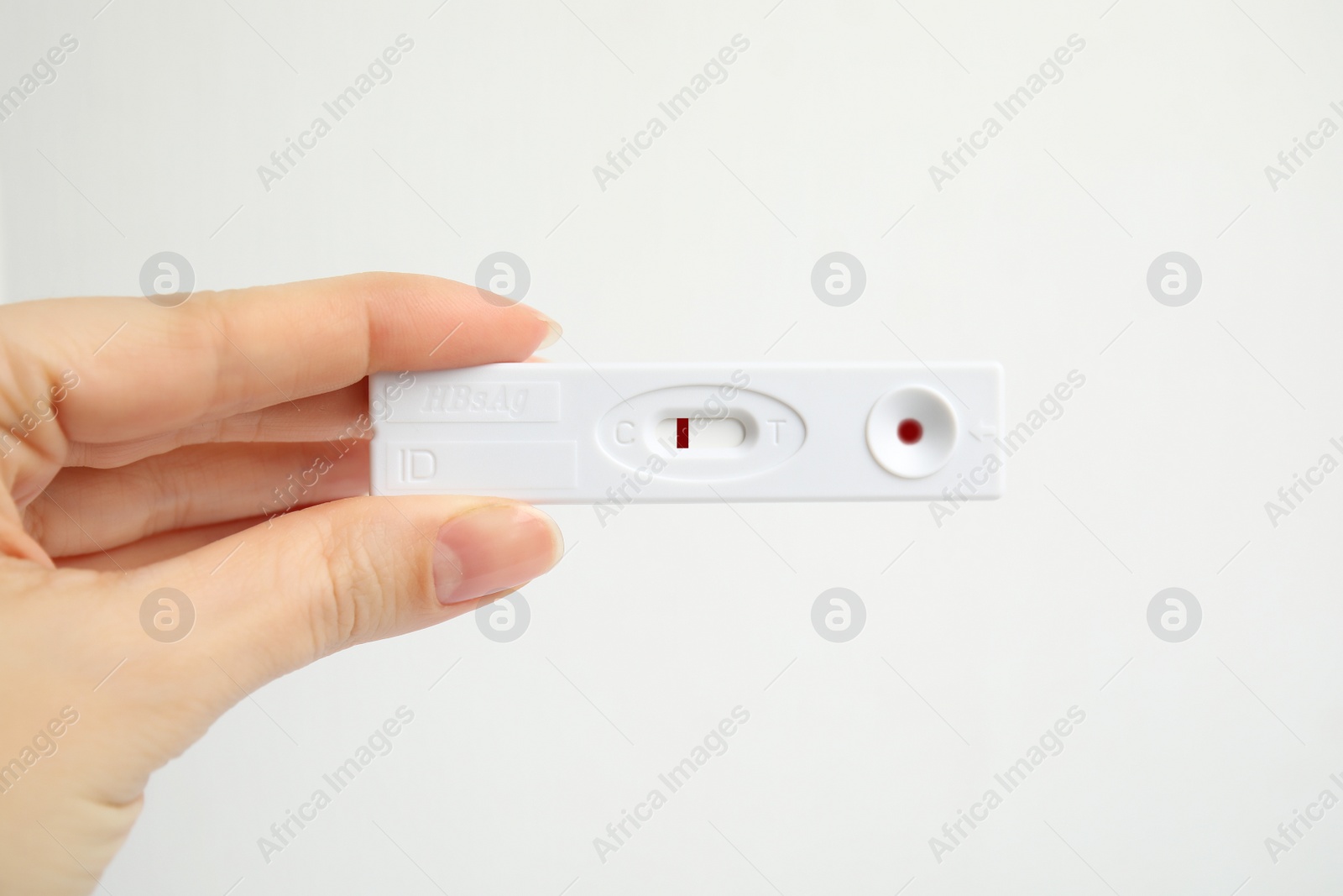 Photo of Woman holding disposable express test for hepatitis on white background, closeup