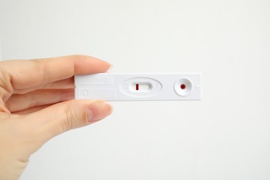 Photo of Woman holding disposable express test for hepatitis on white background, closeup