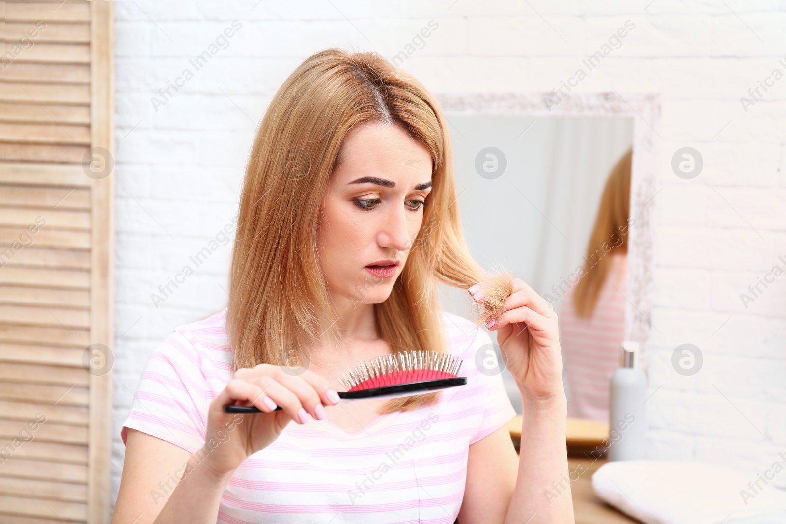 Photo of Emotional young woman brushing hair in bathroom
