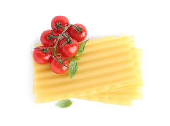 Photo of Uncooked lasagna sheets, cherry tomatoes and basil isolated on white, top view