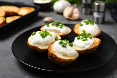 Photo of Delicious potato wedges with sour cream dressing on grey table, closeup