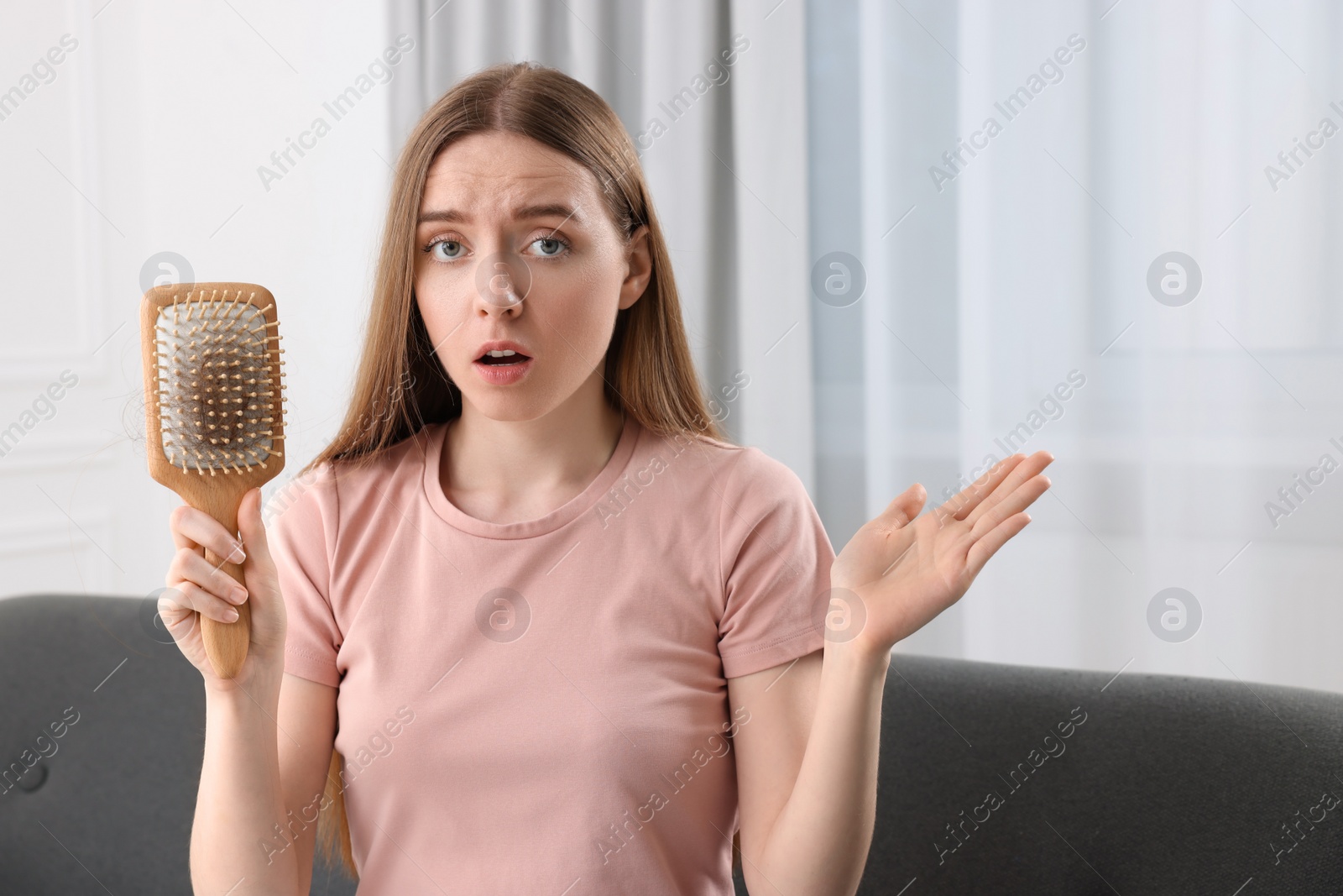 Photo of Emotional woman holding brush with lost hair at home. Alopecia problem