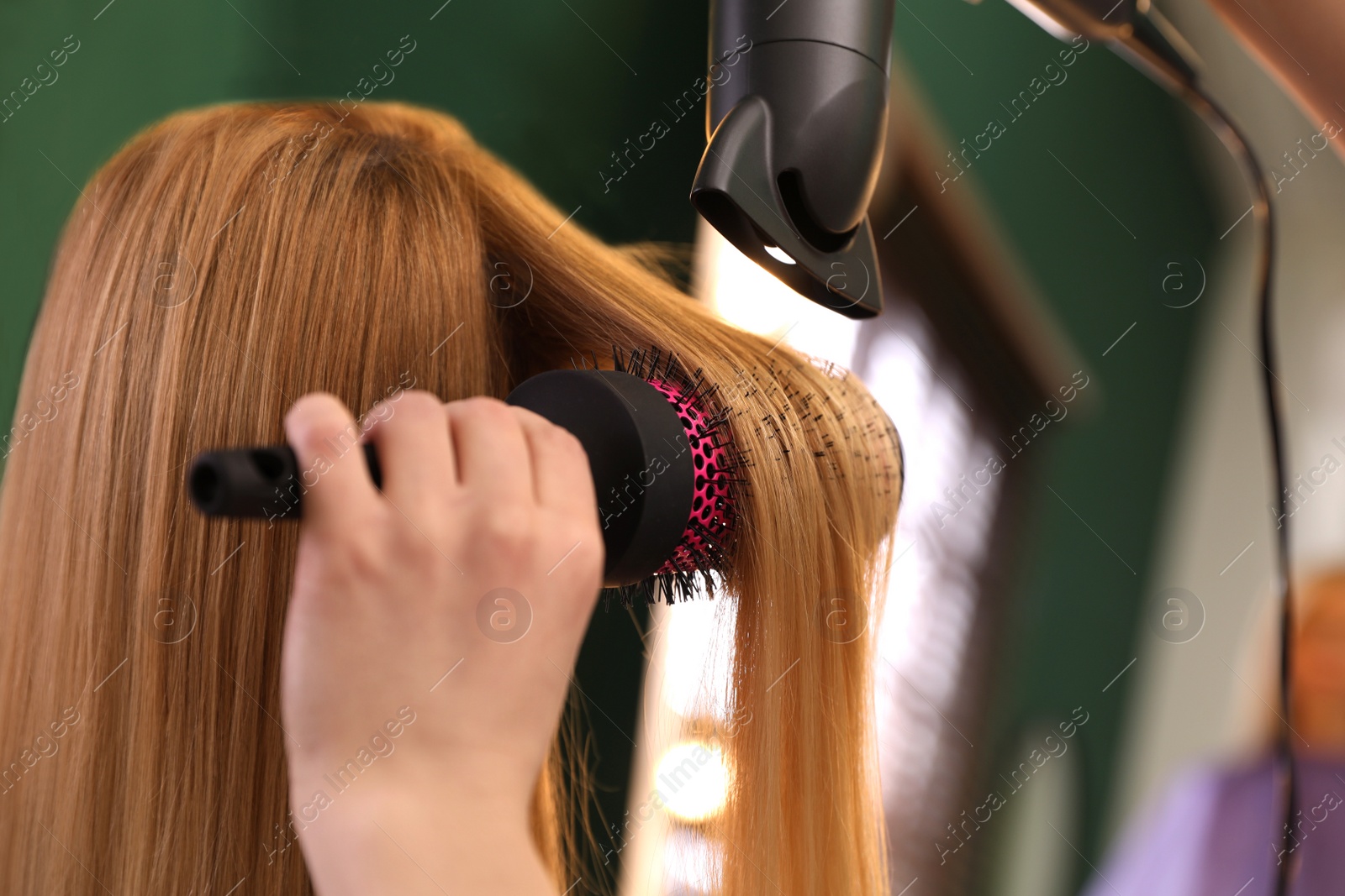 Photo of Stylist blow drying woman's hair in salon