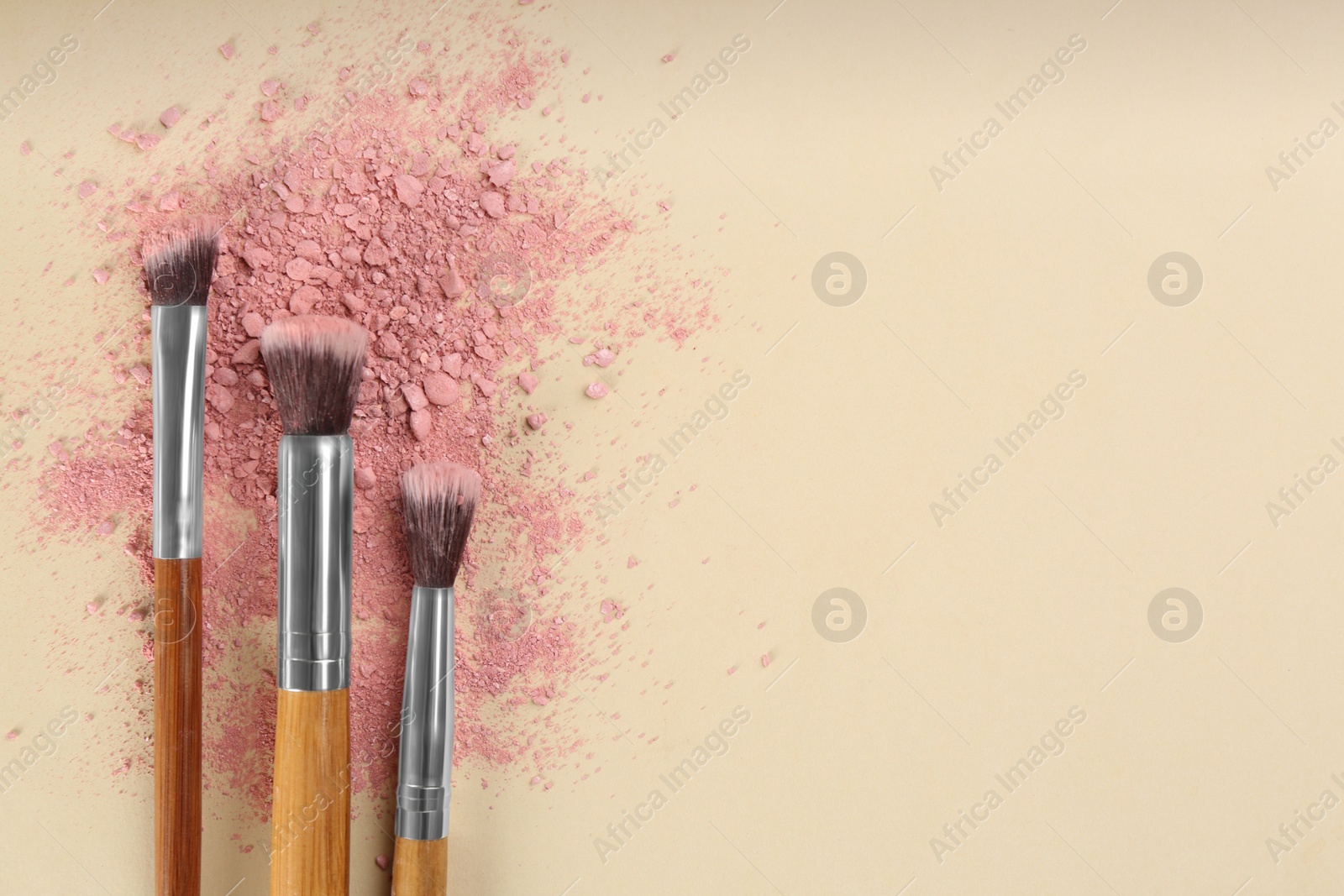 Photo of Makeup brushes and scattered eye shadow on beige background, flat lay. Space for text