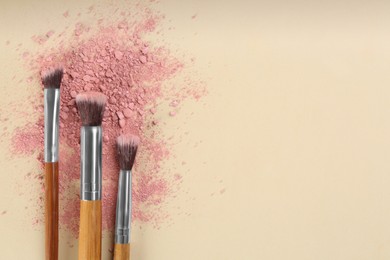 Photo of Makeup brushes and scattered eye shadow on beige background, flat lay. Space for text