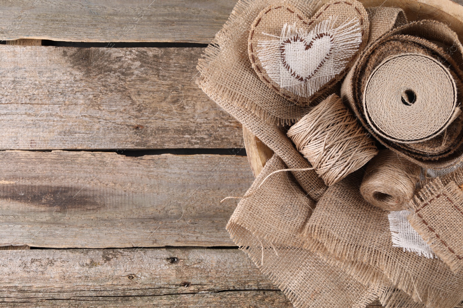 Photo of Pieces of burlap fabric and spools of twine on wooden table, top view. Space for text