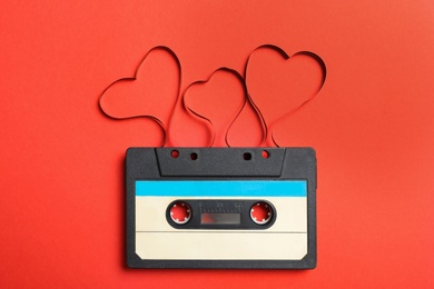 Photo of Music cassette and hearts made with tape on red background, top view. Listening love song