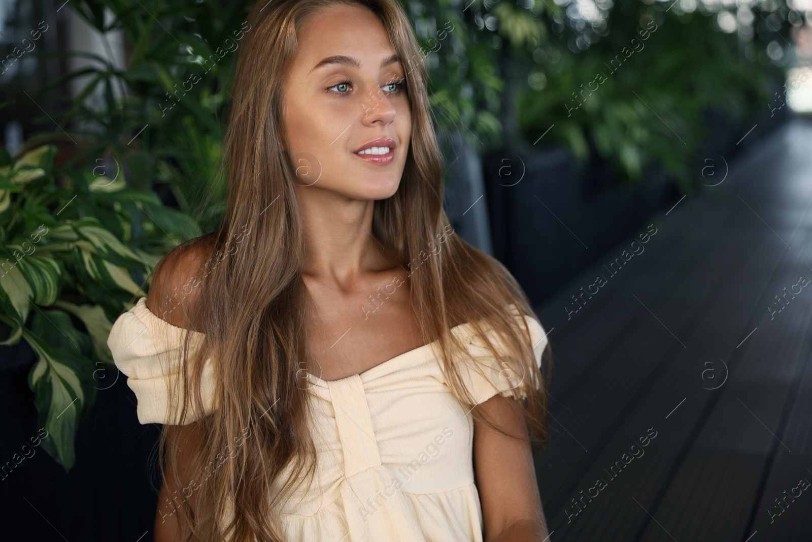 Photo of Beautiful young woman sitting on indoor terrace in cafe, space for text