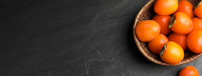 Image of Delicious fresh persimmons on black slate table, top view with space for text. Banner design