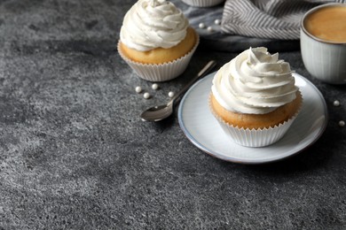 Delicious cupcakes with cream and cup of coffee on grey table. Space for text